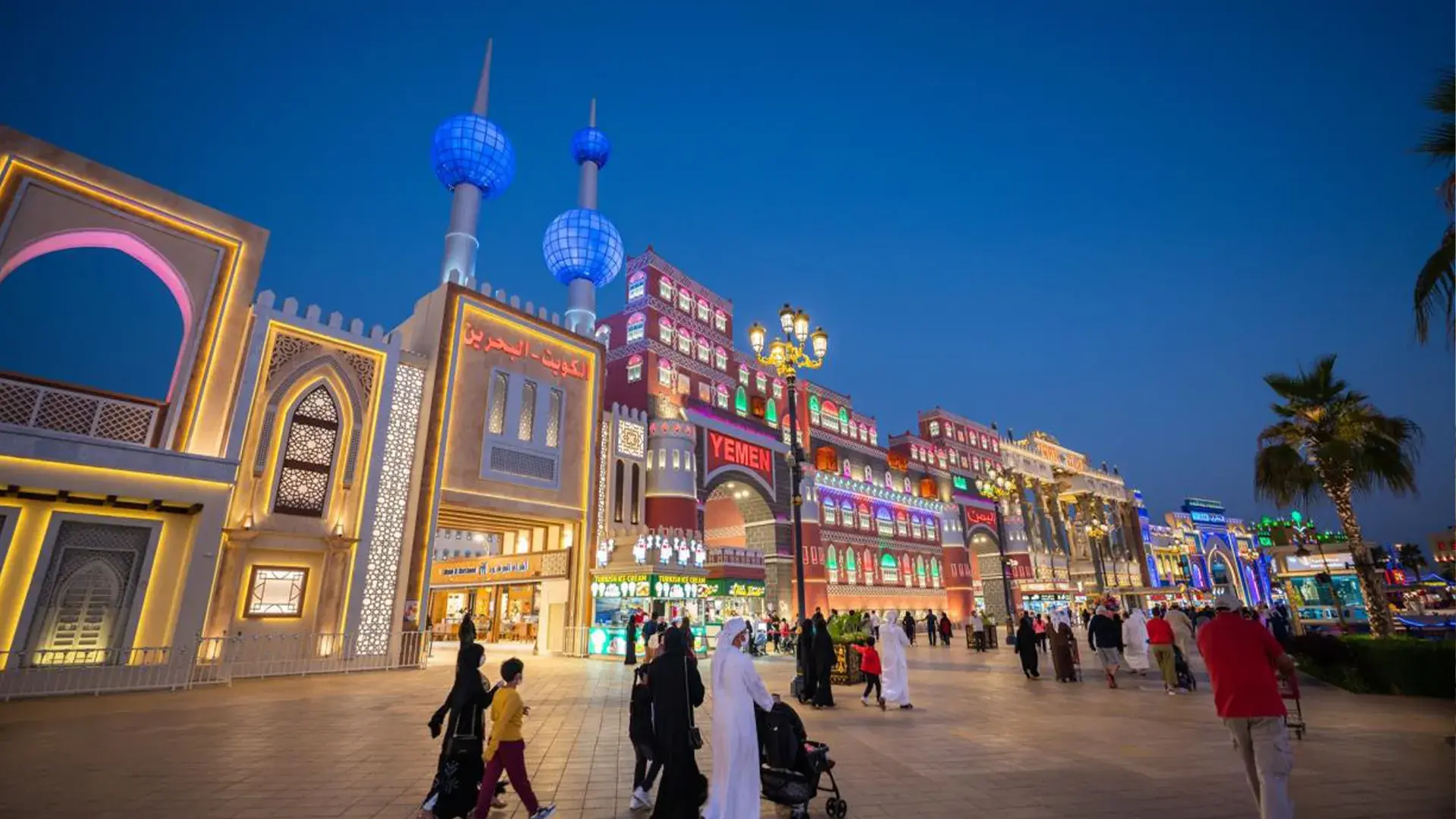A wide view of the illuminated international pavilions and bustling walkways at Global Village Dubai during the night festival.